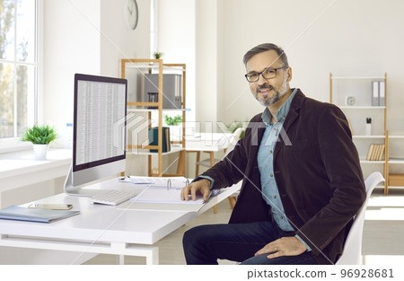 Businessman or financial accountant sitting at his office desk with a desktop computer Businessman or financial accountant sitting at his office desk with a desktop computer 96928681