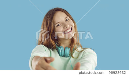 Happy girl with headphones looking at camera and smiling on blue studio background Happy girl with headphones looking at camera and smiling on blue studio background 96928682