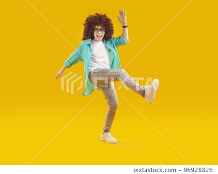 Happy cheerful funny boy in red curly wig, dressed in casual clothes, fooling around and dancing in cheerful mood. Happy cheerful funny boy in red curly wig, dressed in casual clothes, fooling around and dancing in cheerful mood. 96928826