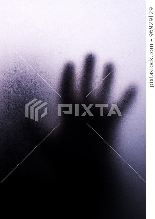 Hand black silhouette behind misted glass in shadows Hand black silhouette behind misted glass in shadows 96929129