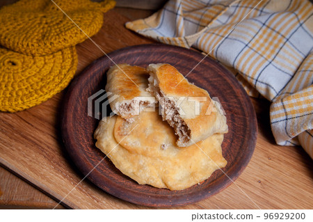 Clay plate of fried meat pies on wooden table. Clay plate of fried meat pies on wooden table. 96929200