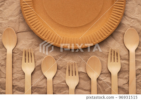 Wooden forks and spoons and paper plate on crumpled paper Wooden forks and spoons and paper plate on crumpled paper 96931515