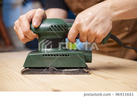 Closeup of carpenter sanding wooden planks with electrical sanding machine 96931681