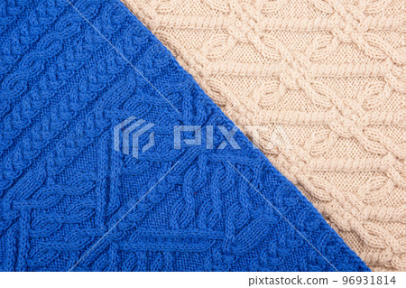 Knitted blue and beige background. Large knitted fabric with a pattern. Close-up of a knitted blanket. Knitted blue and beige background. Large knitted fabric with a pattern. Close-up of a knitted blanket. 96931814