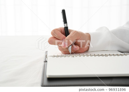 The hand of a young man filling in a system notebook with a pen at a desk The hand of a young man filling in a system notebook with a pen at a desk 96931896