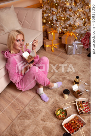 woman eating sushi, asian food restaurant, romantic evening, eating sushi with chopsticks, sushi delivery and takeout, eating at home, romantic dinner alone in christmas decor. Eve New year, saving woman eating sushi, asian food restaurant, romantic evening, eating sushi with chopsticks, sushi delivery and takeout, eating at home, romantic dinner alone in christmas decor. Eve New year, saving 96935350
