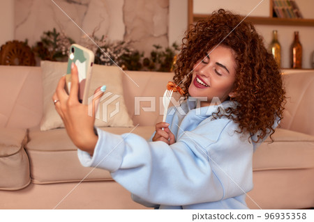 Young woman eating sushi at home. Home food delivery concept. Japan food. Top view. Space for text Young woman eating sushi at home. Home food delivery concept. Japan food. Top view. Space for text 96935358