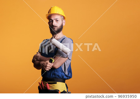 Constructor expert using rolling brush to do painting job, working on renovating project to color walls. Repairman contractor holding roller paintbrush for redecoration and renovation. 96935950