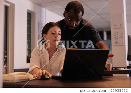 Colleagues working on business project together, looking at laptop in office, discussing company strategy. Diverse corporate workers checking report results at workplace desk in coworking space Colleagues working on business project together, looking at laptop in office, discussing company strategy. Diverse corporate workers checking report results at workplace desk in coworking space 96935952