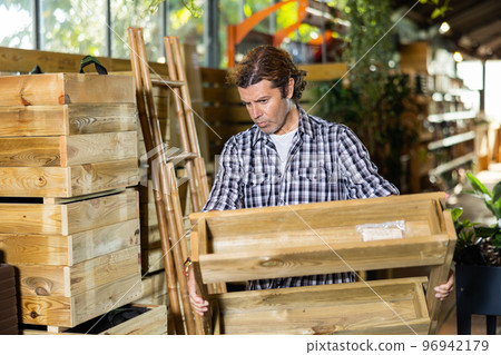 Attentive man choosing wooden pallets in garden store 96942179