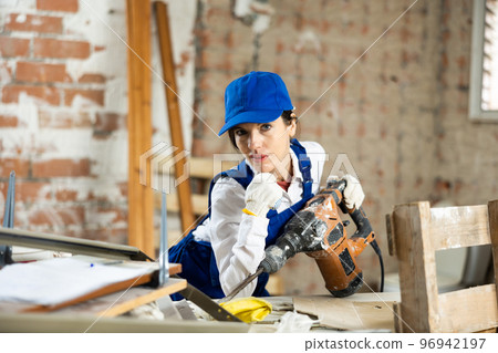 Woman contractor with industrial puncher at construction site closeup Woman contractor with industrial puncher at construction site closeup 96942197