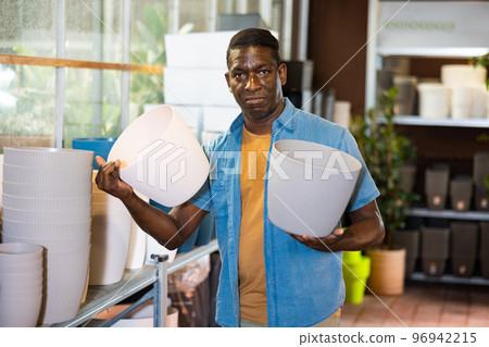 Portrait of african american man choosing pots for flowers and trees in market Portrait of african american man choosing pots for flowers and trees in market 96942215