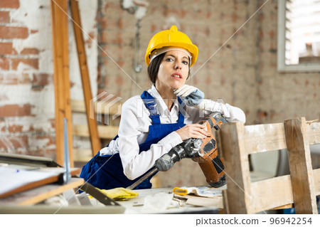 Portrait of female builder with an industrial puncher in her hands 96942254