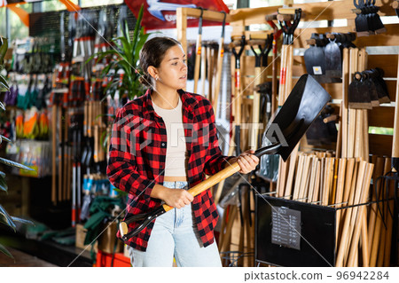 Female farmer choosing shovel in gardening store 96942284