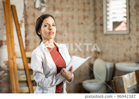 Interested brunette making notes while planning home renovation Interested brunette making notes while planning home renovation 96942387