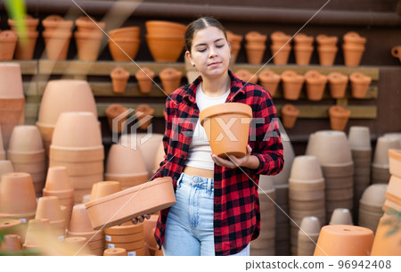 Young girl amateur gardener looking for flowerpots at garden market 96942408