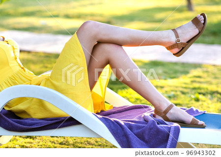 Young woman relaxing outdoors on sunny summer day. Happy lady lying down on comfortable beach chair daydreaming thinking. Calm beautiful smiling girl enjoying fresh air relaxing with closed eyes. Young woman relaxing outdoors on sunny summer day. Happy lady lying down on comfortable beach chair daydreaming thinking. Calm beautiful smiling girl enjoying fresh air relaxing with closed eyes. 96943302