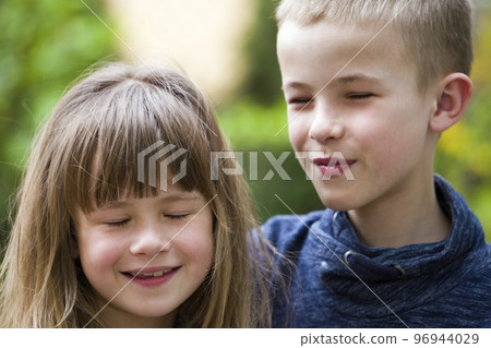 Two cute fair-haired children siblings, young boy brother and sister girl outdoors on bright sunny green bokeh background. Family relation, friendship and love concept. Two cute fair-haired children siblings, young boy brother and sister girl outdoors on bright sunny green bokeh background. Family relation, friendship and love concept. 96944029