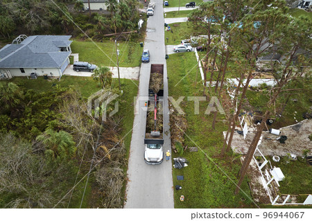 Top view of Hurricane Ian special aftermath recovery dump truck picking up tree branches debris from Florida rural streets. Dealing with consequences of natural disaster Top view of Hurricane Ian special aftermath recovery dump truck picking up tree branches debris from Florida rural streets. Dealing with consequences of natural disaster 96944067