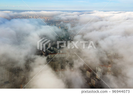 Top aerial view of fluffy white clouds over modern city with high rise buildings. 96944073
