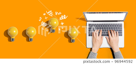 Idea light bulbs with person using a laptop computer Idea light bulbs with person using a laptop computer 96944592
