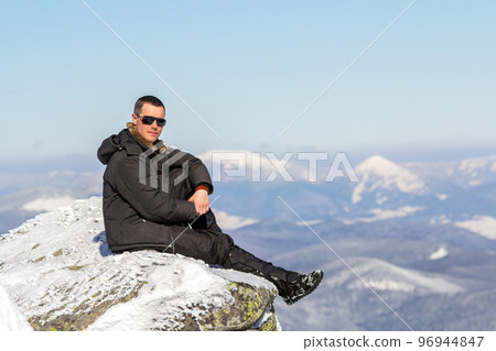 Silhouette of alone tourist sitting on snowy mountain top enjoying view and achievement on bright sunny winter day. Adventure, outdoors activities, healthy lifestyle. Silhouette of alone tourist sitting on snowy mountain top enjoying view and achievement on bright sunny winter day. Adventure, outdoors activities, healthy lifestyle. 96944847