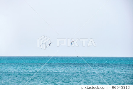 People sportsmen windsurfing and kite surfing in blue ocean water. Summer extreme exotic sport concept 96945513