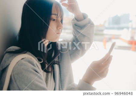 A picture of a high school girl holding a smartphone in the city 96946048