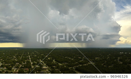 Landscape of dark ominous clouds forming on stormy sky during heavy thunderstorm over rural town area 96946326