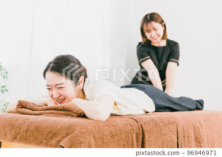 An Asian woman who feels pain after massaging her leg and a masseuse, therapist, chiropractor, and physical therapist 96946971
