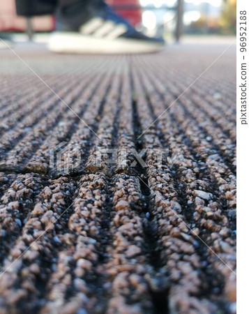 運動鞋以特寫鏡頭顯示在瀝青地面的背面 96952188