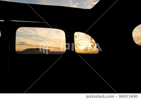 從一輛廢棄的汽車裡看到的日落 96953490