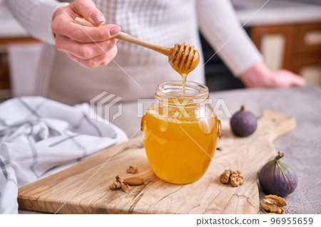 Woman pours honey into a glass jar Woman pours honey into a glass jar 96955659