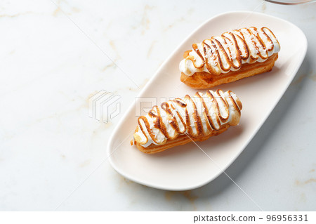 Eclairs with cream decorating of Swiss meringue frosting 96956331