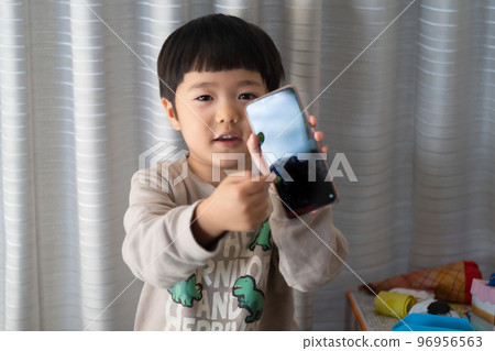 一個 5 歲的男孩展示智能手機顯示屏並說“就是這樣” 一個 5 歲的男孩展示智能手機顯示屏並說“就是這樣” 96956563