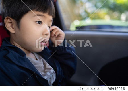 一個5歲的男孩因為在車裡出門時有點困而揉眼睛 96956618