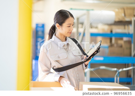 Young female worker inspecting in warehouse Young female worker inspecting in warehouse 96956635