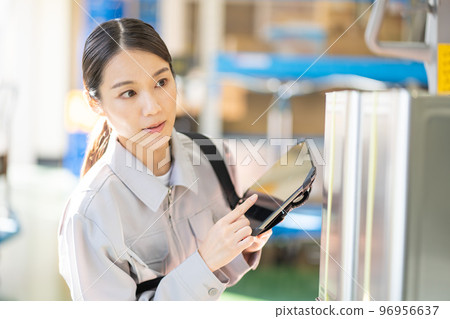 Young female worker inspecting in warehouse Young female worker inspecting in warehouse 96956637
