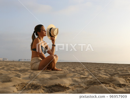 Woman on the beach at sunrise 96957909
