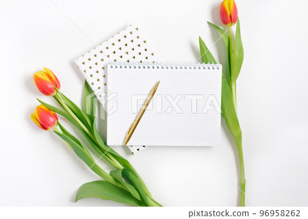 Open spiral notepad with pen and red tulips on white desk background. Template for advertising or visualization of blog with copy space for text. Business holiday Valentine card. Spring and Birthday. Open spiral notepad with pen and red tulips on white desk background. Template for advertising or visualization of blog with copy space for text. Business holiday Valentine card. Spring and Birthday. 96958262