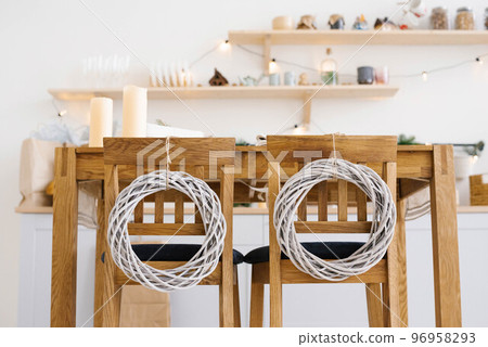 Wooden kitchen chairs decorated with Christmas wreaths in Scandinavian cuisine Wooden kitchen chairs decorated with Christmas wreaths in Scandinavian cuisine 96958293