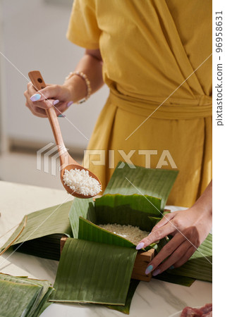 Hands of woman filling wooden mold with rice when making Banh tet cake 96958631