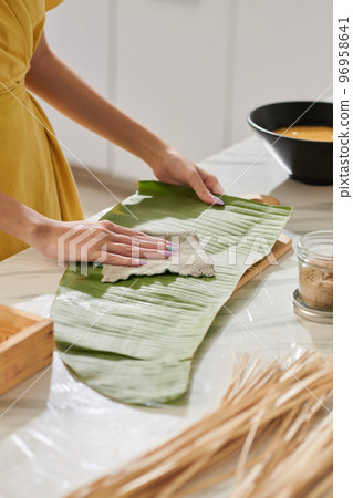 Woman wiping banana leaf for packing square cake 96958641