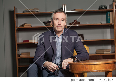 Confident mature businessman looking at camera and holding eye glasses in office 96959107