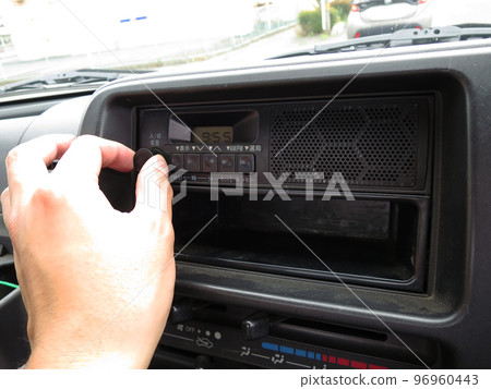 通過轉動旋鈕調節汽車車載收音機的音量 96960443