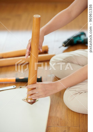 Woman attaching leg to coffee table, furniture restoration concept Woman attaching leg to coffee table, furniture restoration concept 96961386