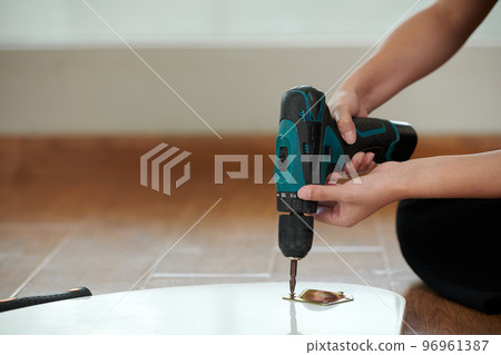 Closeup image of woman drilling table surface, diy concept Closeup image of woman drilling table surface, diy concept 96961387