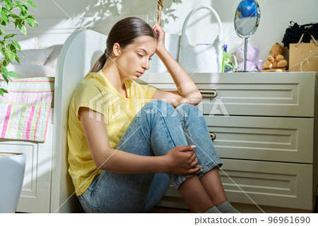 Sad teenage girl sitting on the floor at home 96961690