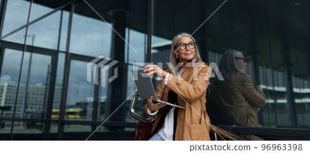 caucasian senor businesswoman at the entrance to the office building caucasian senor businesswoman at the entrance to the office building 96963398