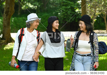 Happy senior women friends and asian girl talking to each other and walking in the park with in a spring time 96963490